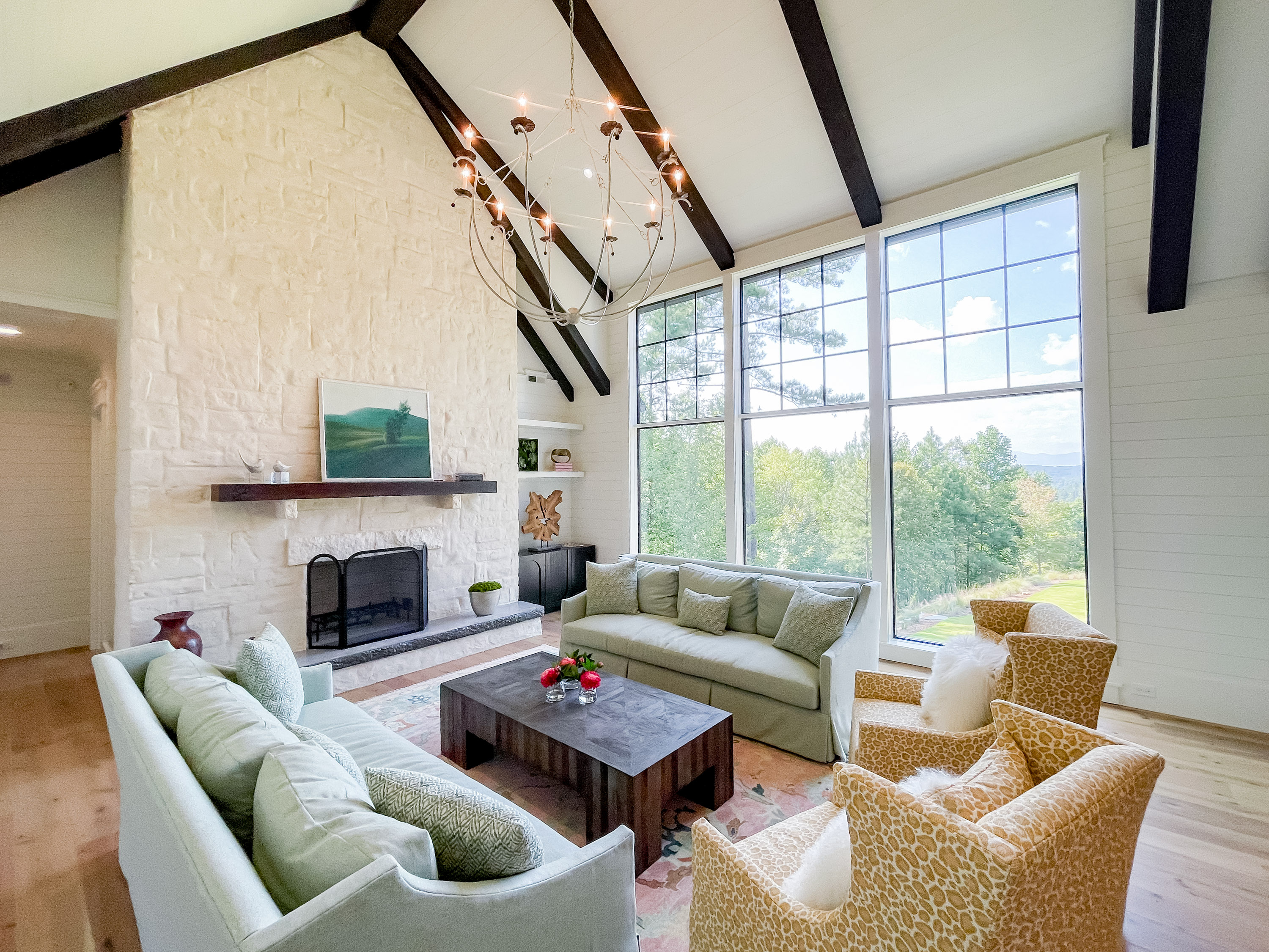 Great room with vaulted ceiling, exposed wood beams, stone fireplace, and floor-to-ceiling windows — The Cliffs interior design by Mac & Morgan Interiors